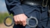 Detail of a police officer holding handcuffs. Selective focus with shallow depth of field.