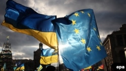 Ukraine -- Two men hold EU and Ukrainian flags during the pro-European protests rally on Independent Square in Kyiv, December 5, 2013